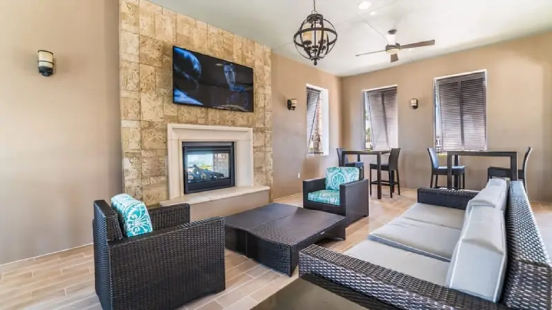 Living area – A spacious living area with a stone wall, a flat-screen TV, wicker furniture, a fireplace, and a ceiling fan.