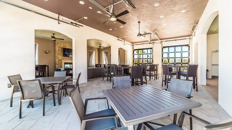 Dining – A spacious outdoor dining area with multiple tables and chairs, a ceiling fan, and large windows providing natural light.