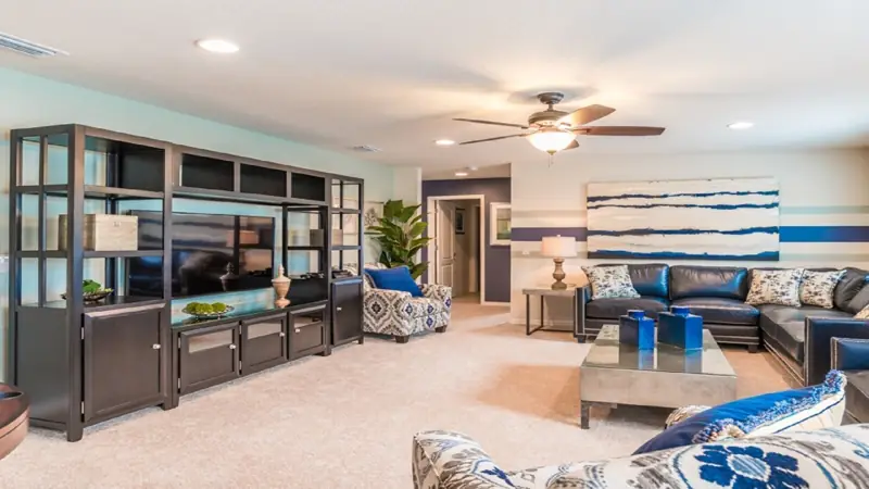 upstairs loft – A modern living room with a glass-fronted entertainment unit, a ceiling fan, and a sectional sofa.