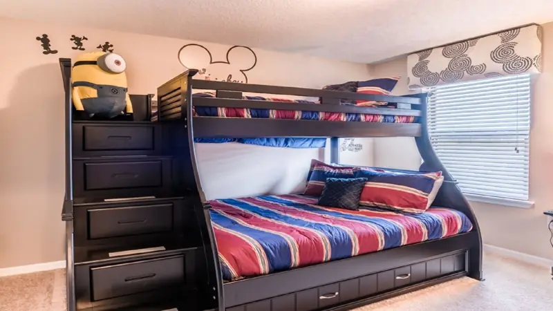 bunk beds twin over full and full trundle, could sleep 5 children – A bunk bed with a desk and drawers, a Minion plush toy, and a Mickey Mouse wall decal.